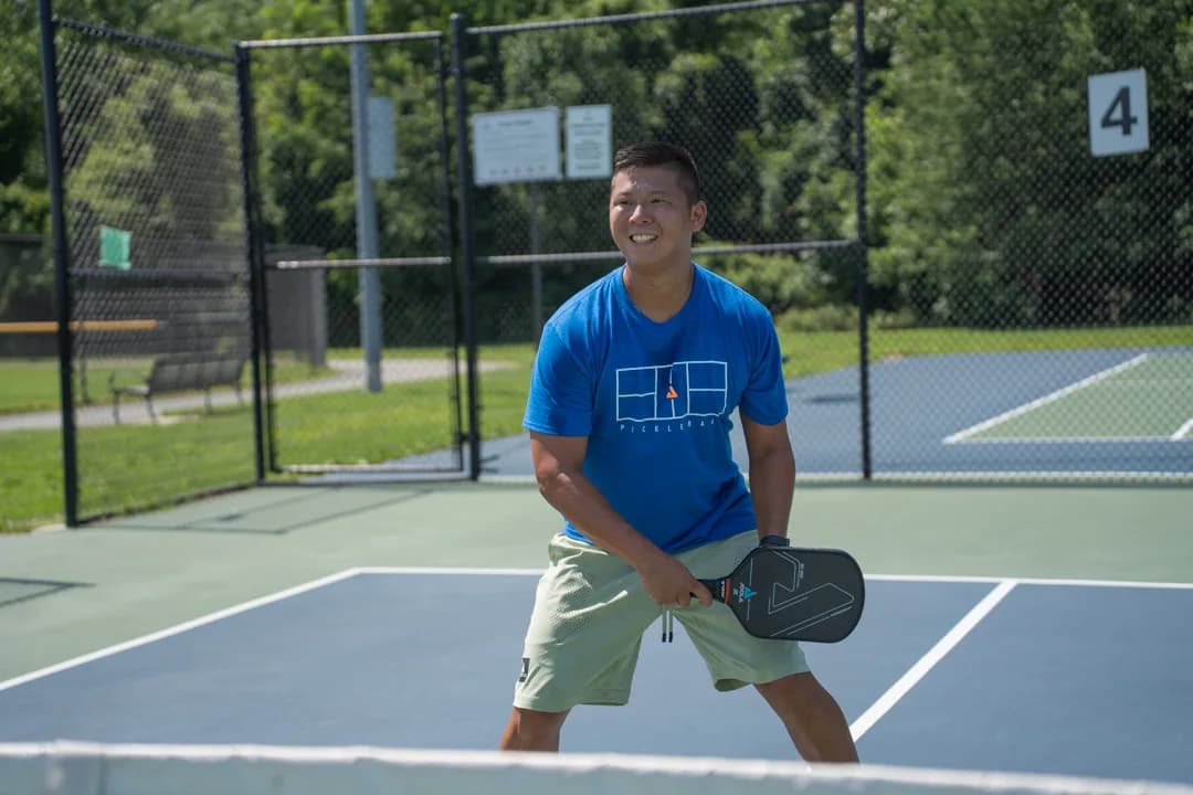 Sam Morris smiling with his paddle in a ready stance on an outdoor court.